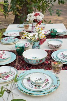 the table is set with plates, cups and vases