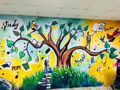 a mural painted on the side of a building with children's books under a tree