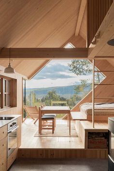 an open kitchen and dining area in a wooden cabin with large windows overlooking the mountains