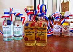 three bottles of liquor sitting on top of a table next to each other with red, white and blue ribbons around them