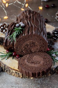 a sliced chocolate cake on a wooden board with pine cones and evergreen needles around it