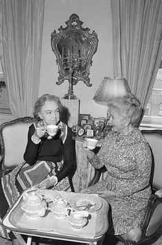 two women sitting at a table drinking tea