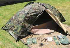 an army tent set up in the grass with its contents laid out on it's side