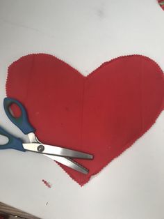 a pair of scissors sitting on top of a heart shaped piece of paper with red felt