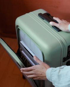 a person holding onto a green piece of luggage