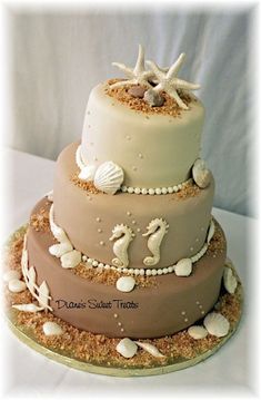 a three tiered cake with shells and seahorses on top