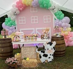 there is a table with balloons and farm animals on it in front of a pink house