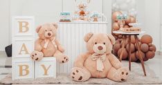 two brown teddy bears sitting next to each other in front of a baby shower sign