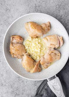 a white plate topped with chicken and rice next to a pair of black jeans on a gray surface