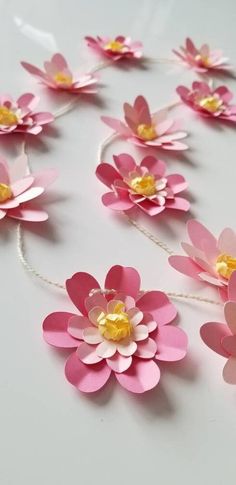 pink paper flowers with yellow centers on a white table top, ready to be cut into smaller pieces