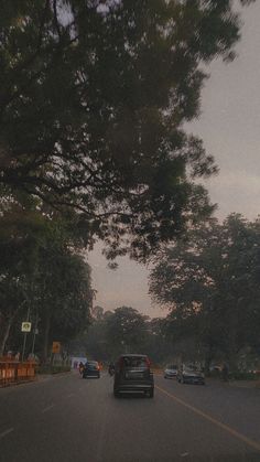 cars are driving down the street in front of some trees