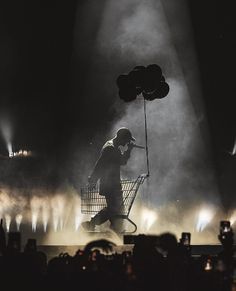 a man is pushing a shopping cart on stage with balloons in the shape of hearts