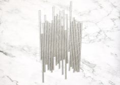 a bunch of metal rods on a white marble surface with black and grey lines in the middle