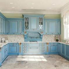 a large kitchen with blue cabinets and marble counter tops on both sides of the room