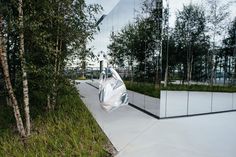 a large mirrored building with trees in the foreground and an umbrella hanging from it's side