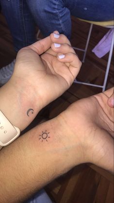 two people with matching wrist tattoos on their arms, one has a sun and the other has a moon