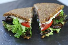 a sandwich with lettuce, tomatoes and other toppings on a black plate