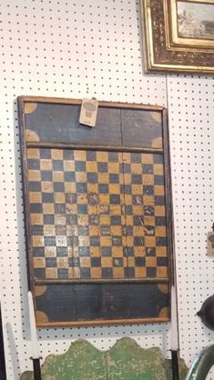 an old chess board on display in a room with two chairs and a painting hanging on the wall