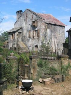 an old stone house with a large bowl on the ground in front of it's entrance