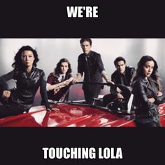 a group of people standing next to each other in front of a red car with the words we're touching loa on it