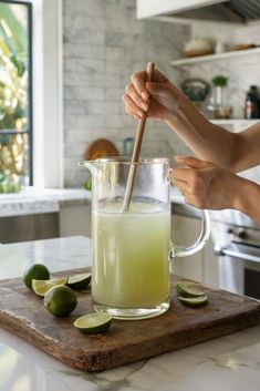 a woman is stirring limeade into a pitcher