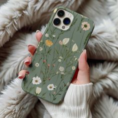 a woman holding up her phone case with flowers on it