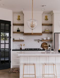 a kitchen with white cabinets and gold accents on the counter tops, along with two bar stools