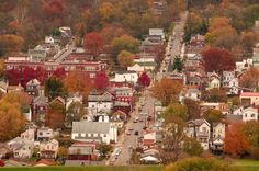 a small town with lots of houses and trees in the fall colors on both sides