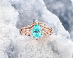 a ring with an aqua stone surrounded by diamonds on top of some ice flakes