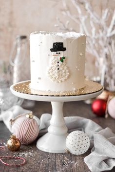 a white frosted cake sitting on top of a wooden table next to ornaments and baubles