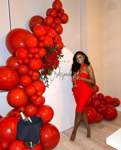 a woman in a red dress standing next to a display of balloons