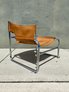 a tan leather chair sitting on top of a cement floor next to a gray wall