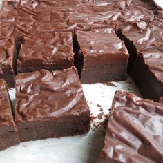 there are many pieces of chocolate cake on the counter top and one is cut into squares