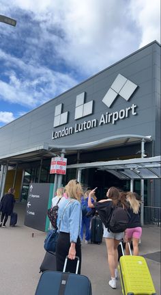 several people with suitcases are walking towards the london loton airport terminal on a sunny day