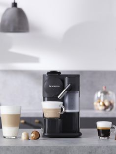 an espresso machine sitting on top of a counter next to two cups of coffee