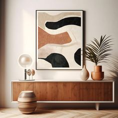 an abstract painting hangs on the wall above a wooden cabinet