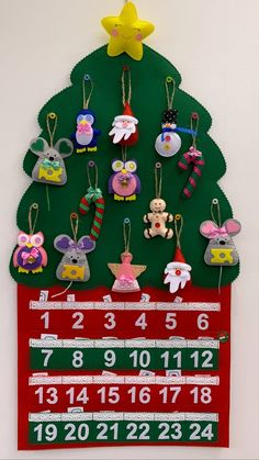 a christmas tree shaped calendar hanging on a wall with ornaments attached to the front and sides