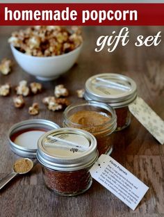 four jars filled with different kinds of food on top of a wooden table next to a spoon