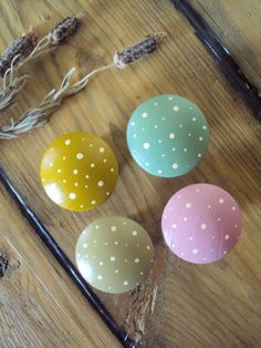 four painted eggs sitting on top of a wooden table next to some string and twine