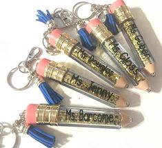 six lipstick shaped key chains with writing on them, one is pink and the other is blue