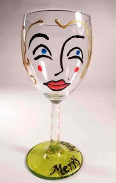 a wine glass with a face painted on the side and words written in gold lettering