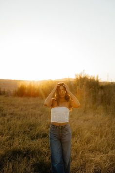 a woman standing in a field with her hands on her head