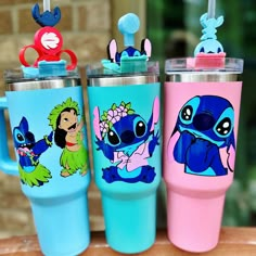 three different colored tumblers with cartoon characters on them