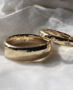 two gold wedding rings with the words my sun on them sitting on a white cloth