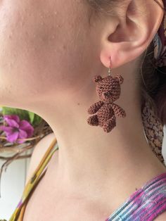 a woman wearing earrings with a teddy bear on it