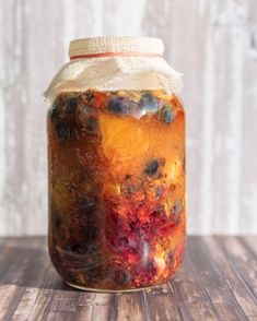 a jar filled with liquid sitting on top of a wooden table