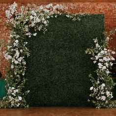 an arrangement of white flowers and greenery in front of a brick wall at a wedding