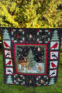 a quilted christmas tree with deers and birds on it in front of some trees