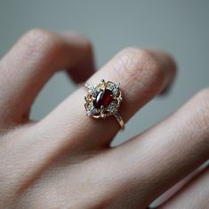 "We all shine on...like the moon and the stars and the sun..." A beautiful blood-red garnet set in solid sterling silver with a layer of 14k yellow gold, orbited by sparkly CZs like the stars. A stunning cosmic ring for the ages. Available in yellow gold, rose gold and silver, and 14K solid gold. Gold vermeil or 14k solid gold Natural 6x4mm garnet center stone Round CZs (what's this?) ** This item is specially made for you. Please allow 1-2 week lead time. ShippingDomestic: Free standard shippin Gold Garnet Cluster Promise Ring, Heirloom Gold Cluster Ring With Garnet, 14k Gold Red Cluster Ring With Rose Cut Diamonds, Gold Garnet Birthstone Ring With Center Stone, Hallmarked Red Garnet Birthstone Ring, Heirloom Garnet Cluster Ring With Gemstones, Red Oval Garnet Cluster Ring, Red 14k Gold Cluster Ring With Birthstone, Gold Oval Garnet Cluster Ring