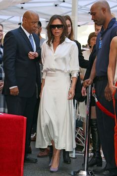 a woman in a white dress is standing next to other people